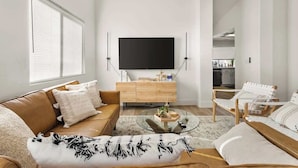 En moderne stue med sofa, sofabord og fjernsyn.