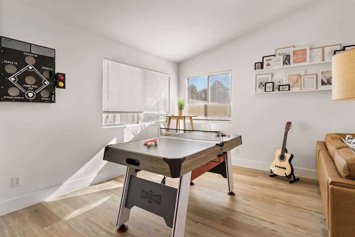 A room with a foosball table, a guitar, and a wall-mounted game board.