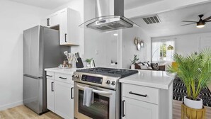 A modern kitchen with stainless steel appliances, white cabinetry, and a central island. - Radiant Pool Retreat: 4BR NLV Getaway (North Las Vegas)