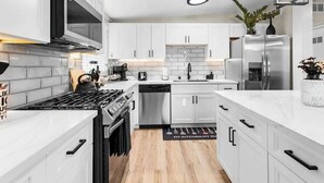Una cocina moderna con armarios blancos, electrodomésticos de acero inoxidable y encimera de mármol.