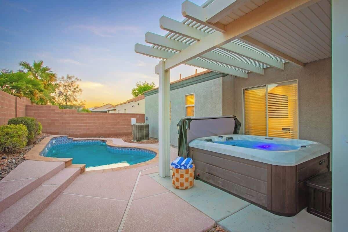 Ein Garten mit Swimmingpool, Whirlpool, einer Pergola und einer überdachten Terrasse.