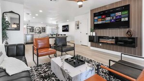 Een moderne woonkamer met een flatscreen televisie, een plafondventilator en een open haard.