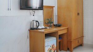 A room with a wooden desk, a television mounted on the wall, a wardrobe, and a fan. - Bohemia Hotel (Ho Chi Minh City)