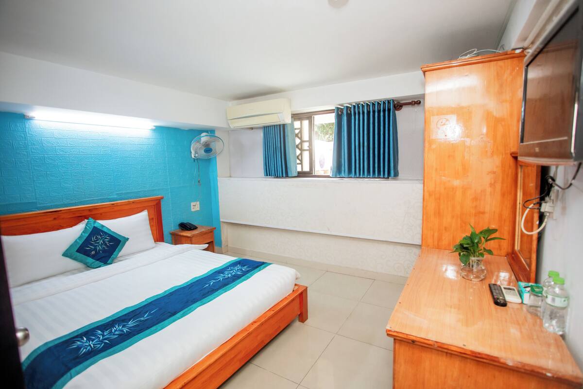 Una habitación de hotel con cama, mesita de noche y un armario de madera.