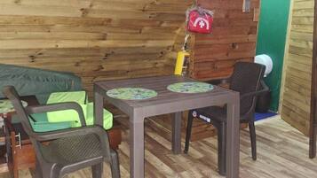 A wooden interior with a table, chairs, and a green wall with plants.