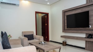 Una sala de estar moderna con un sofá, una mesa de centro, un televisor y una puerta.