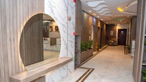 Un vestíbulo de hotel moderno con suelo de mármol, detalles de madera y un mostrador de recepción.