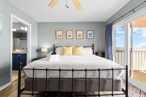 A bedroom with a bed, a nightstand, a lamp, and a view of the outdoors. - Bayfront Paradise-Steps to Sand, Pool, Kayaking (Pensacola)