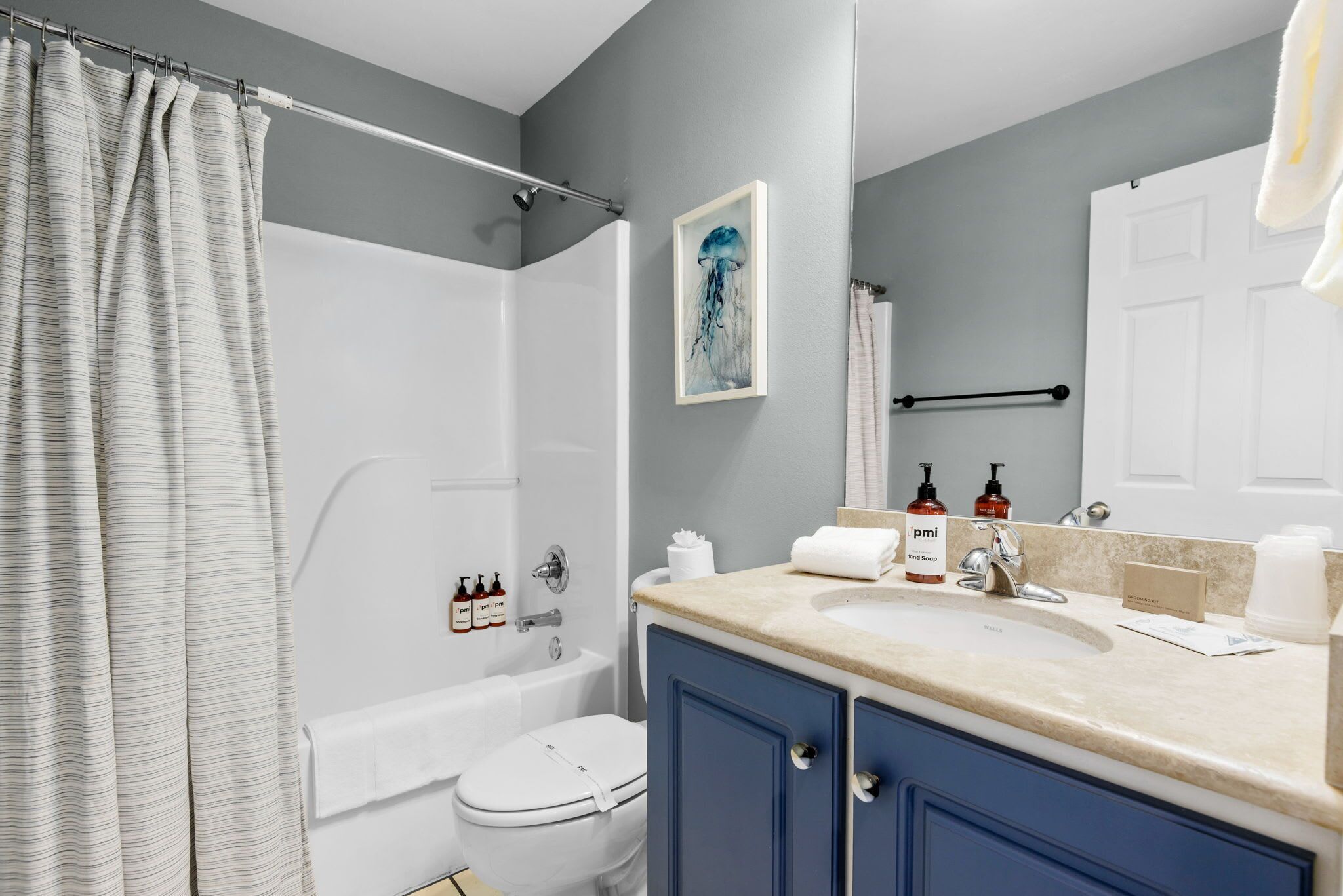 A bathroom with a shower, toilet, bathtub, and a sink with toiletries.