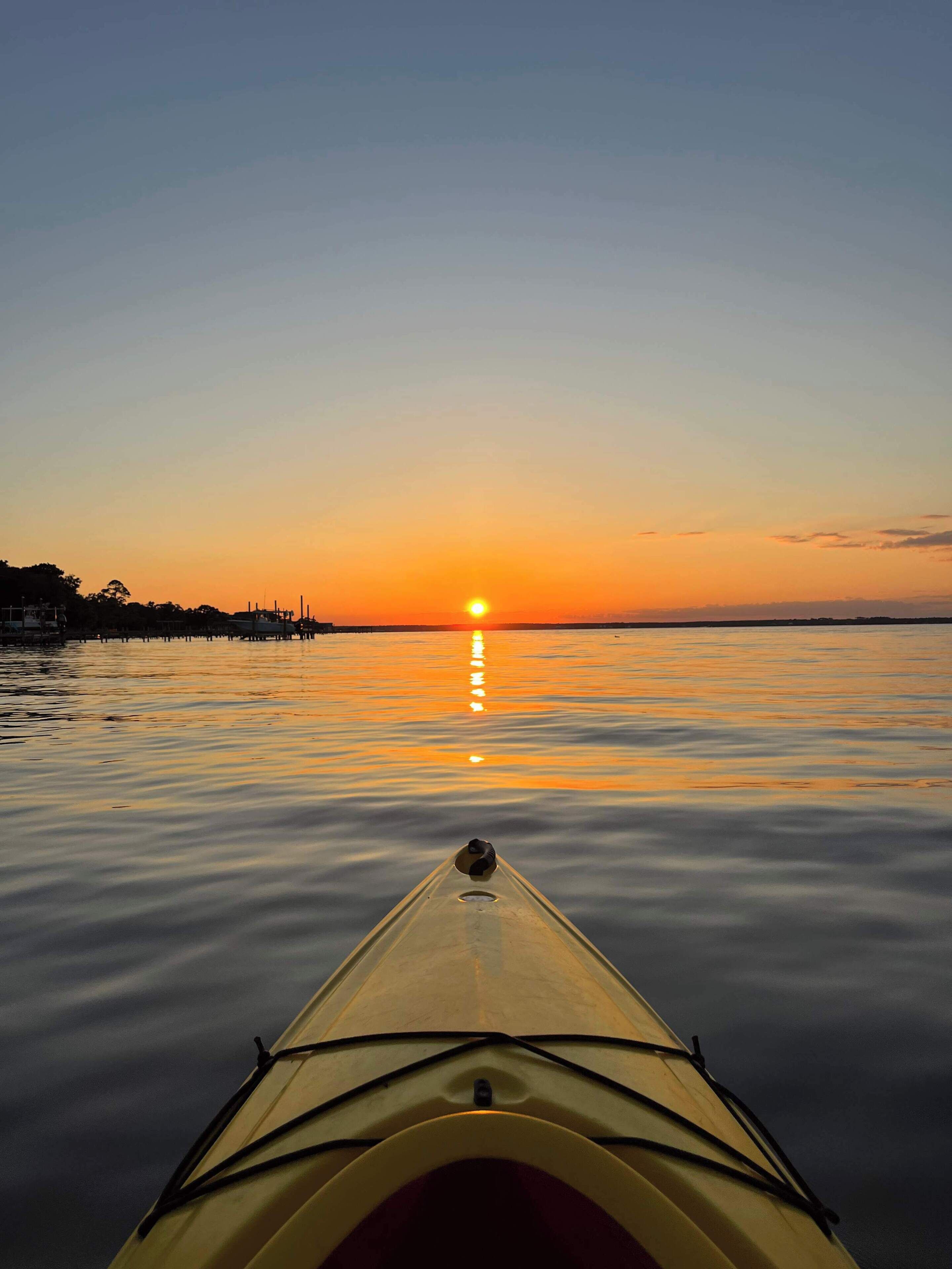 Un kayak di fronte a un tramonto sull'acqua calma.