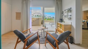 A modern living room with a view of a pool and outdoor area, wooden furniture, and a small table with a plant. - Tracadero Lodge PH C7 - 2 Hab Apto (Dominicus)