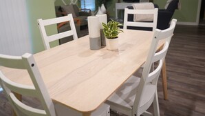 A dining table with white chairs, a potted plant, and a remote control on the table. - Unwind in this serene thoughtfully designed home nestled in a quiet neighborhood (Poinciana)