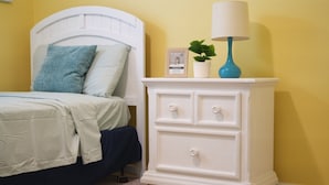 A bedroom with a bed, a nightstand with drawers, a lamp, and a framed picture. - Unwind in this serene thoughtfully designed home nestled in a quiet neighborhood (Poinciana)