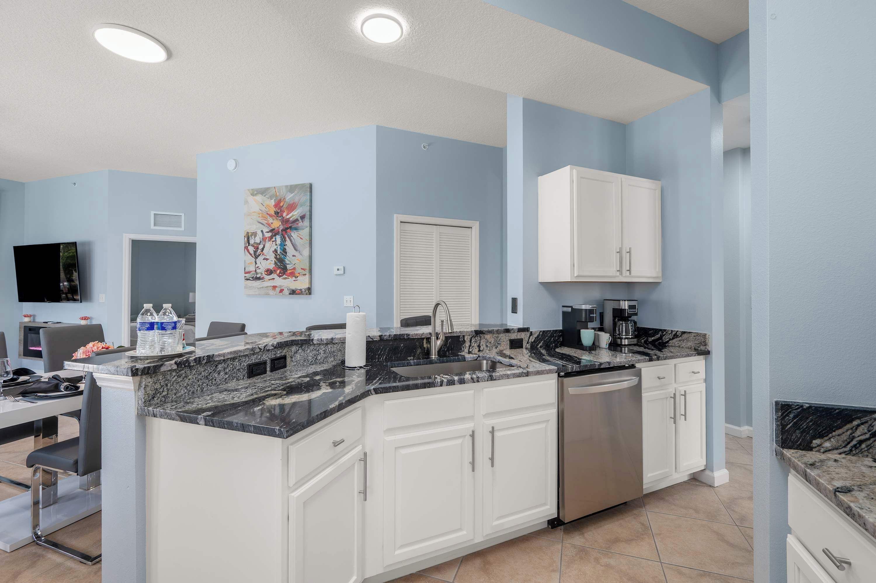 A modern kitchen with white cabinets, a granite countertop, and a stainless steel dishwasher.
