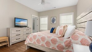 A bedroom with a bed, a television, a dresser, and a window with blinds. - Residence 101S at The Sandcastle Condominiums (Wildwood Crest)