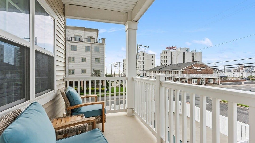 Un balcon doté de meubles en osier et offrant une vue sur un immeuble sur lequel on peut lire l’inscription « Carhart ».