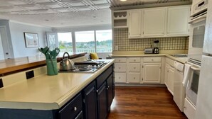 A kitchen with white cabinets, a wooden countertop, a stove, and a view through the window.