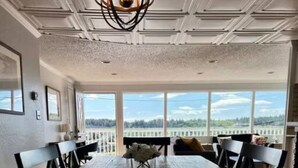 A dining area with a large table, chairs, and a view through large windows.