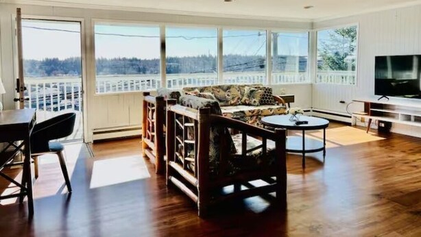 A spacious living room with a large window, a sofa, a coffee table, and a television.