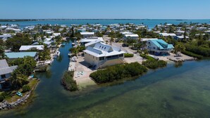 Luftaufnahme eines Küstenresorts mit mehreren Gebäuden, einer Marina und klarem, blauem Wasser.
