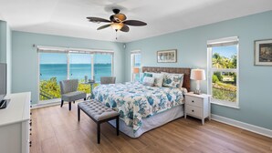 Ein Schlafzimmer mit Bett, Schreibtisch, Stuhl, Bank, Nachttisch, Lampe und Deckenventilator.