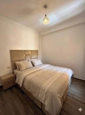 A bedroom with a bed, nightstand, and a hanging light fixture. - Elegance & Serenity (Marrakech)
