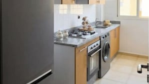 Une cuisine moderne équipée d’un four encastré, d’un lave-linge et d’un réfrigérateur en acier inoxydable.