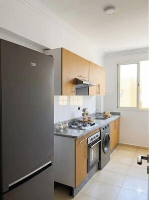 A modern kitchen with a built-in oven, a washing machine, and a stainless steel refrigerator. - Elegance & Serenity (Marrakech)