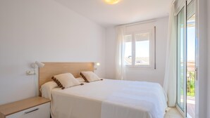 Een slaapkamer met een bed, nachtkastjes, een raam en uitzicht op de omgeving.