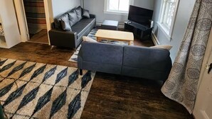Ein Wohnzimmer mit einer Couch, einem Fernseher und einem gemusterten Teppich.