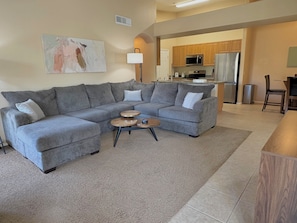 A living room with a grey sectional sofa, a coffee table, and a painting on the wall.