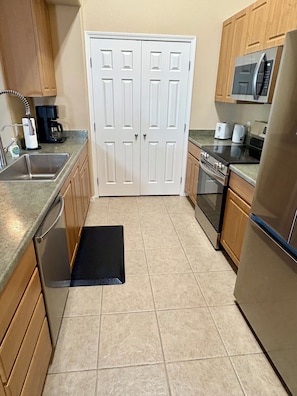 A kitchen with a sink, stove, microwave, and refrigerator.