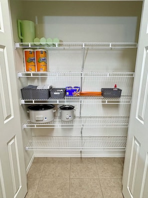 A kitchen pantry with shelves, storage boxes, and kitchen appliances.