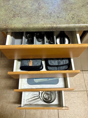 A kitchen drawer with utensils, a strainer, and a small appliance.