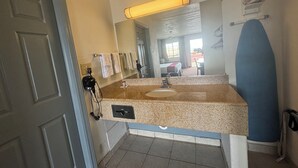 Ein Hotelbad mit Waschbecken, Spiegel, Handtuchhalter und Duschbereich.