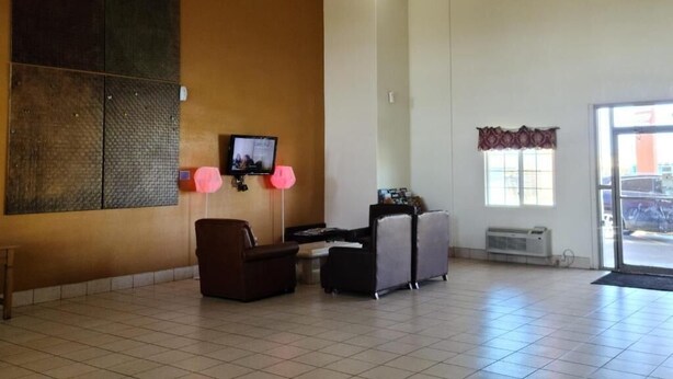 Eine geräumige Lobby mit einem großen Wandbild, einem Fernseher, einer Sitzecke und Blick ins Freie.