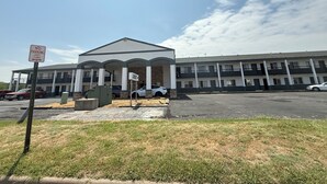 A building with a covered entrance, a sign indicating no parking, and a sign pointing to the lobby. - Budget Host Inn (Salina)