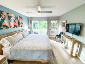 Une chambre à coucher avec un lit, un bureau, une télévision et des œuvres d’art accrochées au mur.