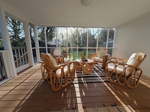 Ein überdachter Außenbereich mit Korbmöbeln und Blick auf den Garten.