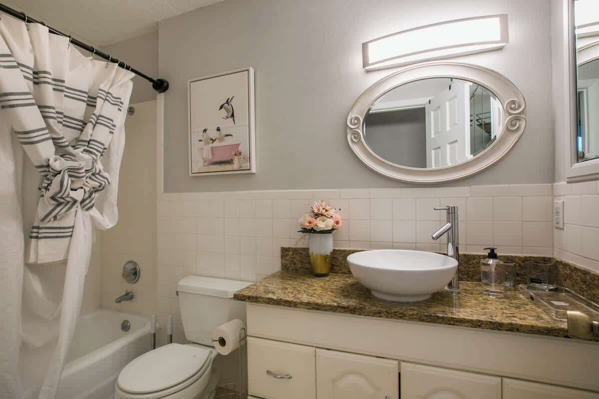 A bathroom with a bathtub, toilet, sink, and a mirror.