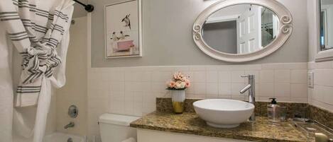 A bathroom with a bathtub, toilet, sink, and a mirror.