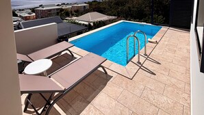 Une piscine sur le toit offrant une vue dégagée sur l’océan et le paysage urbain.