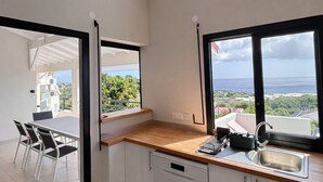 Une cuisine moderne avec vue sur la mer, un coin repas avec des chaises et un lave-vaisselle encastré.