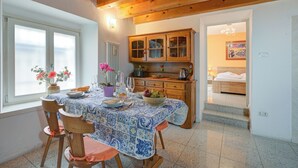 A dining area with a table set for four, wooden chairs, a cabinet with glass doors, and a view into a bedroom. - Vida Boa Apartment with Private Balcony Dining, Torbole sul Garda, Italy (Torbole sul Garda)
