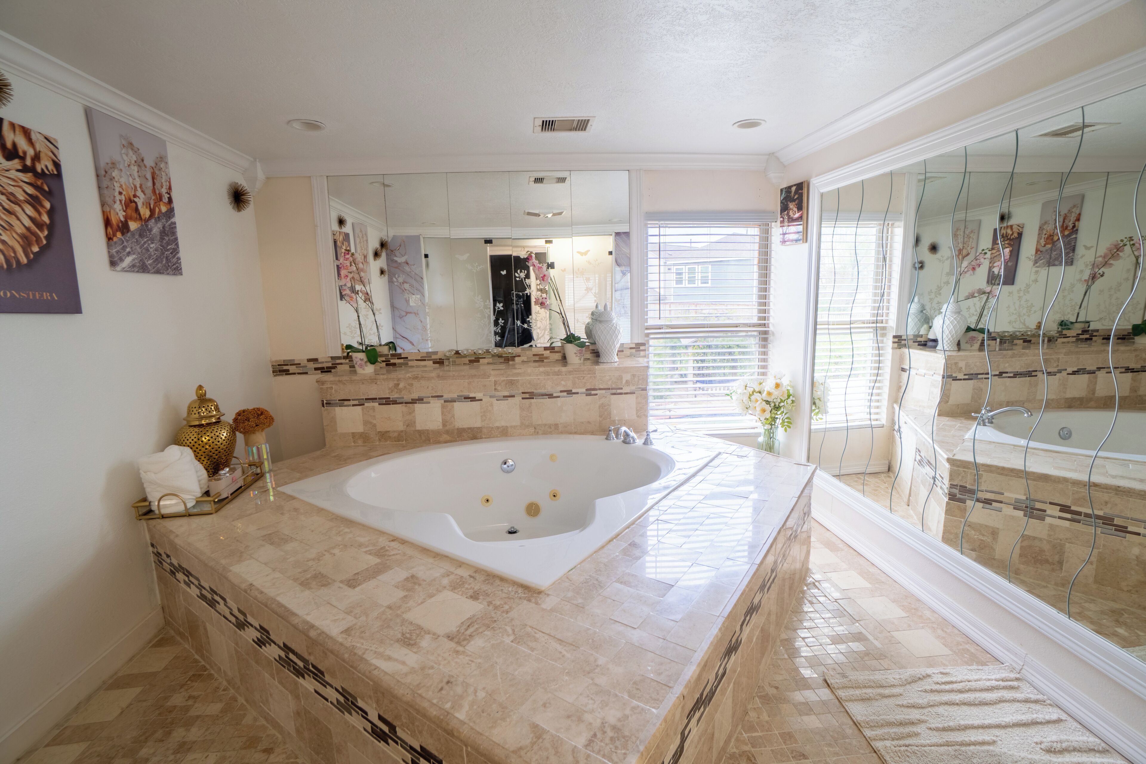 Une salle de bain avec une grande baignoire, un miroir et un sol carrelé.