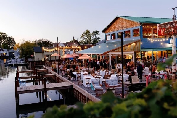 Un restaurante frente al agua con terraza, un muelle y un edificio con un letrero.