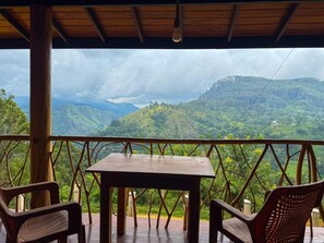 A covered outdoor seating area with a table and chairs, overlooking a mountainous landscape. - Wooden Dream Ella (Ella)