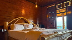 Un lit en bois doté d’une tête de lit au design original, une table de chevet et une vue sur l’extérieur par une fenêtre.