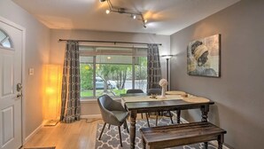 A dining area with a table, chairs, a bench, a lamp, and a painting on the wall. - Silver Modern 2BR: Pet-Friendly Oasis w/ Fenced Private Garden Near Downtown (Carmichael)