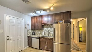 A kitchen with wooden cabinets, a stainless steel refrigerator, and a tiled backsplash. - Silver Modern 2BR: Pet-Friendly Oasis w/ Fenced Private Garden Near Downtown (Carmichael)